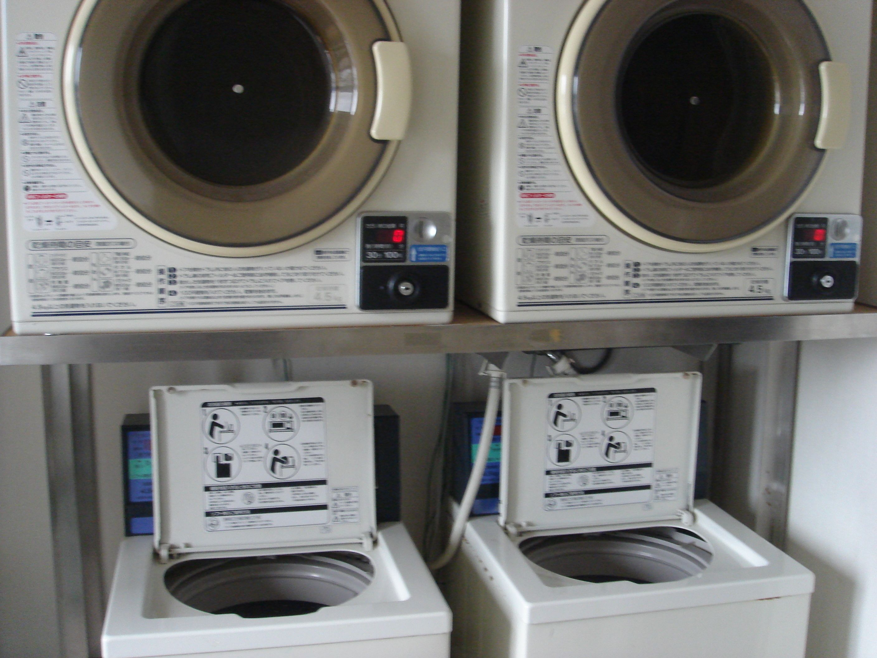 Two stacked washing machines with control panels and instruction manuals.