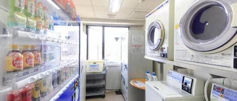 A laundromat with washing machines and a vending machine selling beverages.