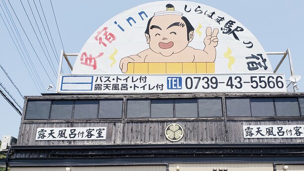 A hotel sign with a sumo wrestler illustration, a contact number, and Japanese text indicating a sumo-themed establishment. - Minshuku Inn Shirahama Ekinoyado (Shirahama)