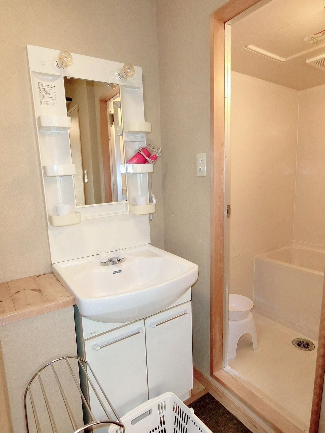 Un baño con lavamanos blanco, espejo y cabina de ducha.