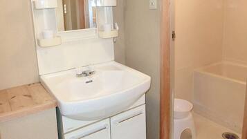 Un baño con lavamanos blanco, espejo y cabina de ducha.