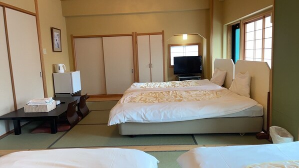 A hotel room with a bed, a desk with a chair, a television, and sliding doors. - Minshuku Inn Shirahama Ekinoyado (Shirahama)