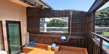 Una terraza de madera con ventana que da a un puente y follaje.