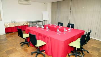 A conference room with a red table, black chairs, and water bottles.