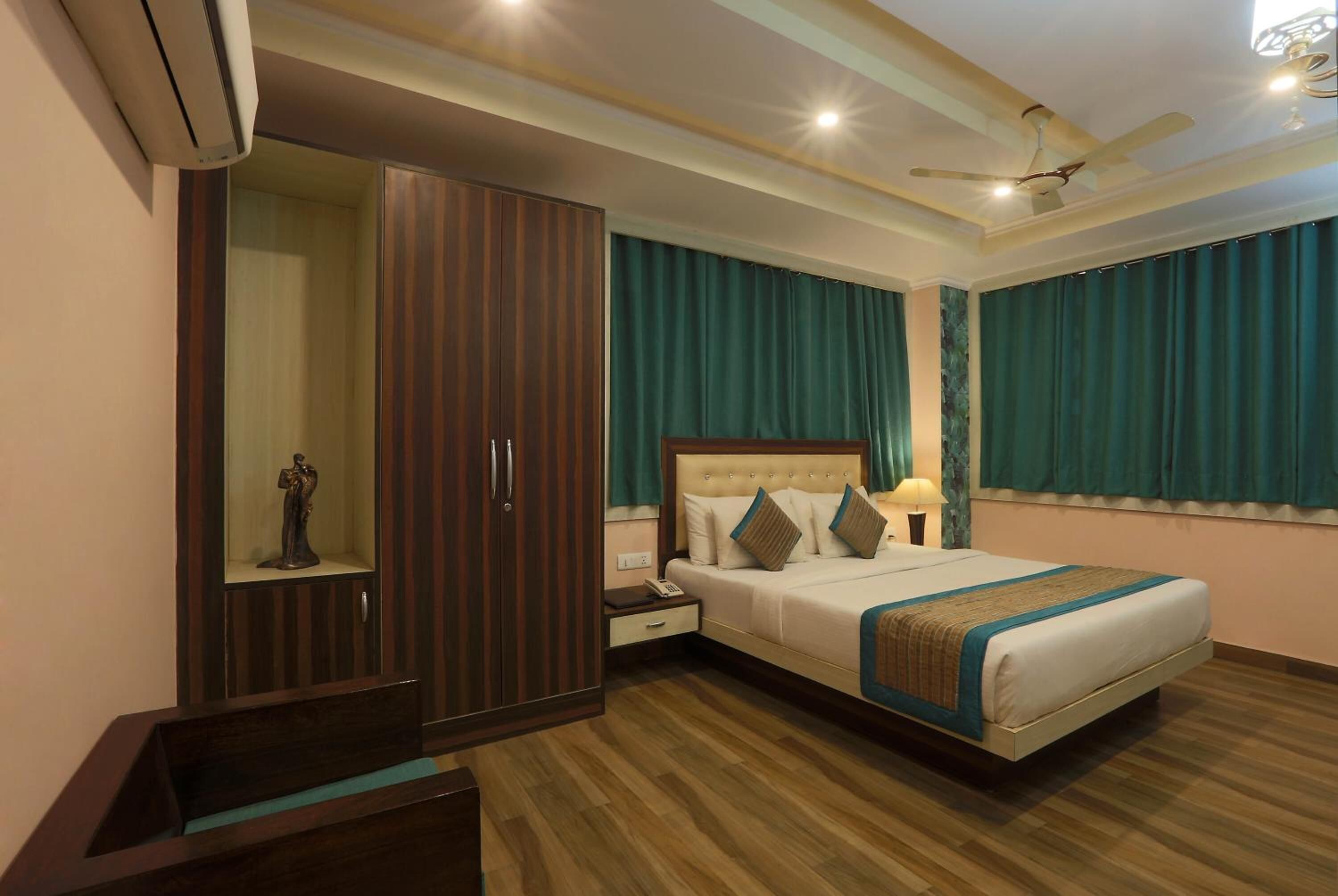 A hotel room with a large bed, a wardrobe, a nightstand, and a ceiling fan.