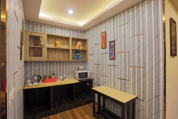Una cocina compacta equipada con microondas, un lavamanos pequeño y un mueble de madera con puertas de vidrio.