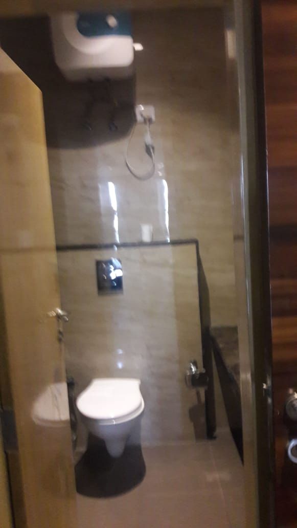 A bathroom with a toilet, a glass partition, and a shower area.