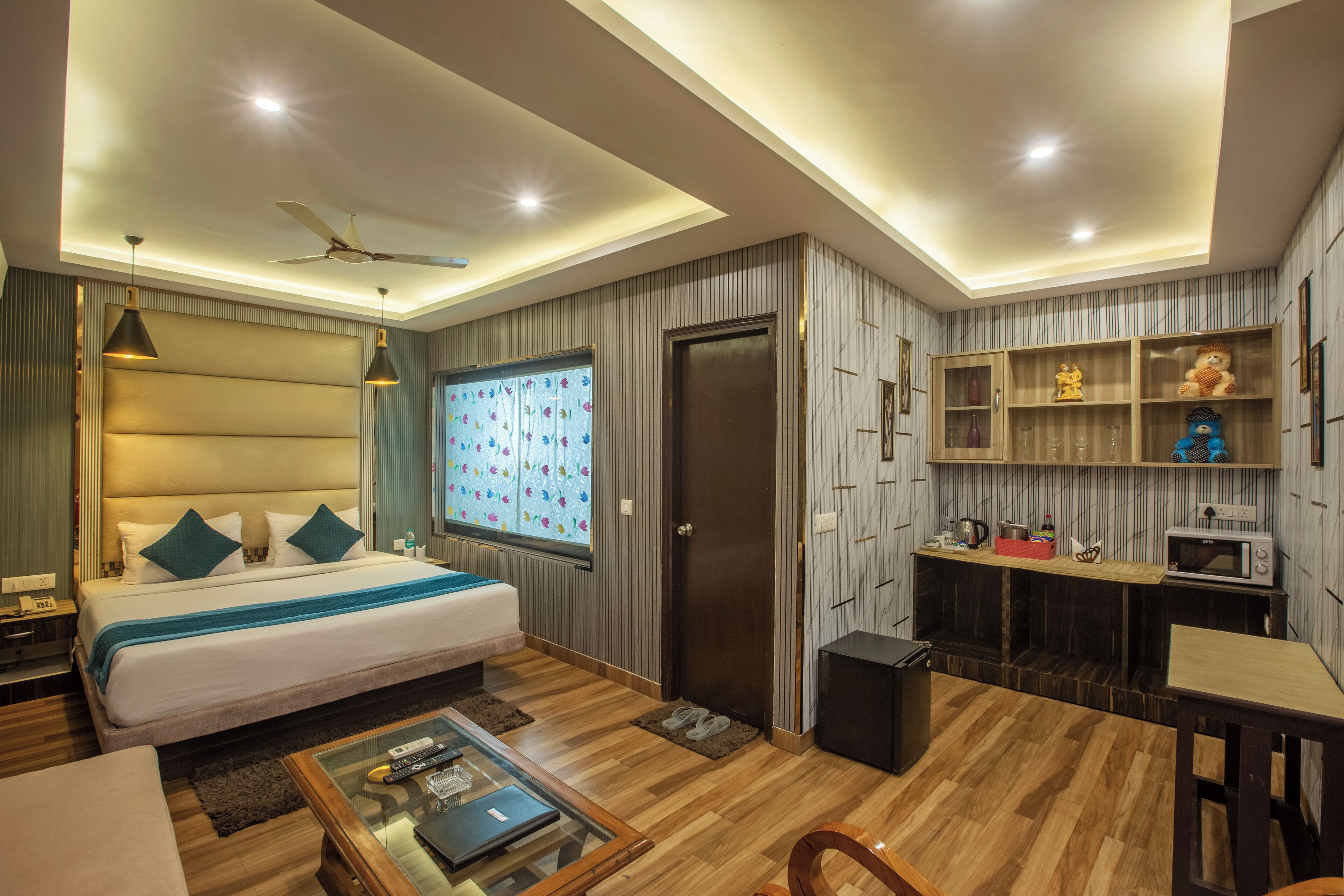 Une chambre d’hôtel moderne dotée d’un grand lit, d’un bureau, d’une kitchenette et d’un ventilateur de plafond.