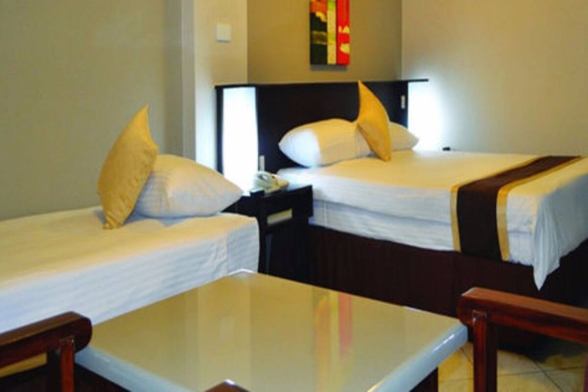 A hotel room with two single beds, a small table, and a nightstand with a phone.