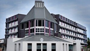 A modern building with a distinctive triangular roof and multiple windows. - Peninsula International Hotel (Suva)