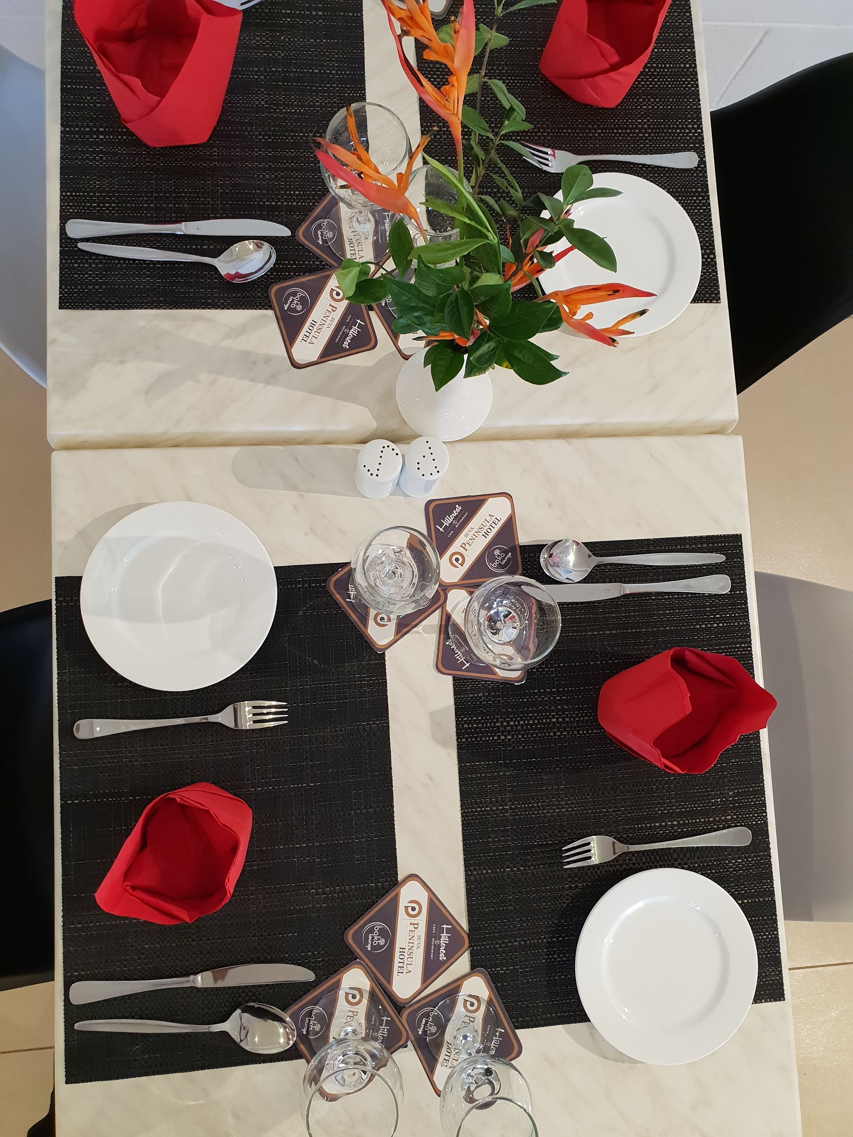 A dining table set with white plates, silverware, and red napkins.