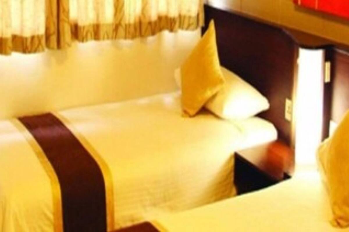 A hotel room with a bed, pillows, and a window with curtains.
