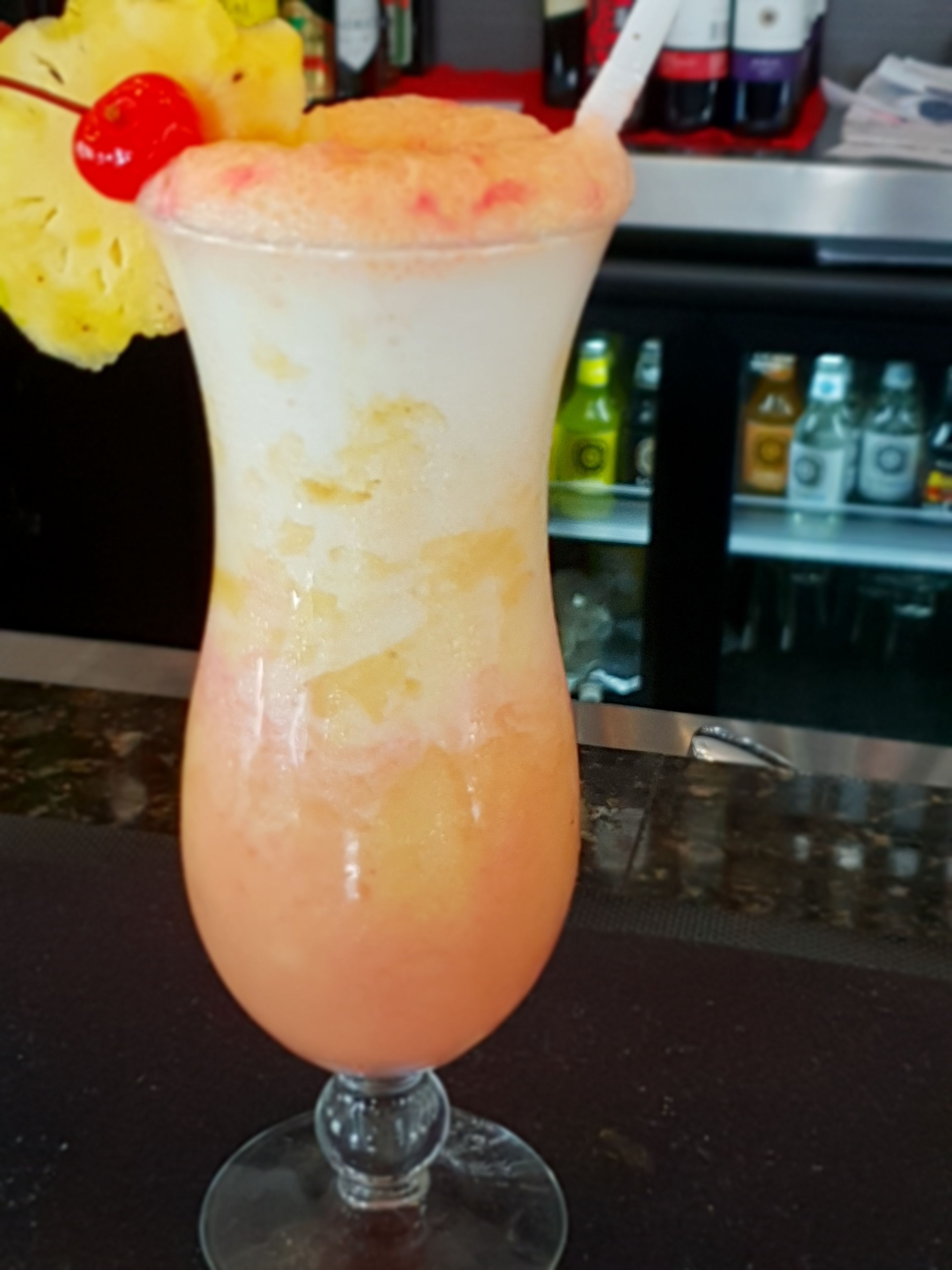 A cocktail in a glass with a cherry on top.
