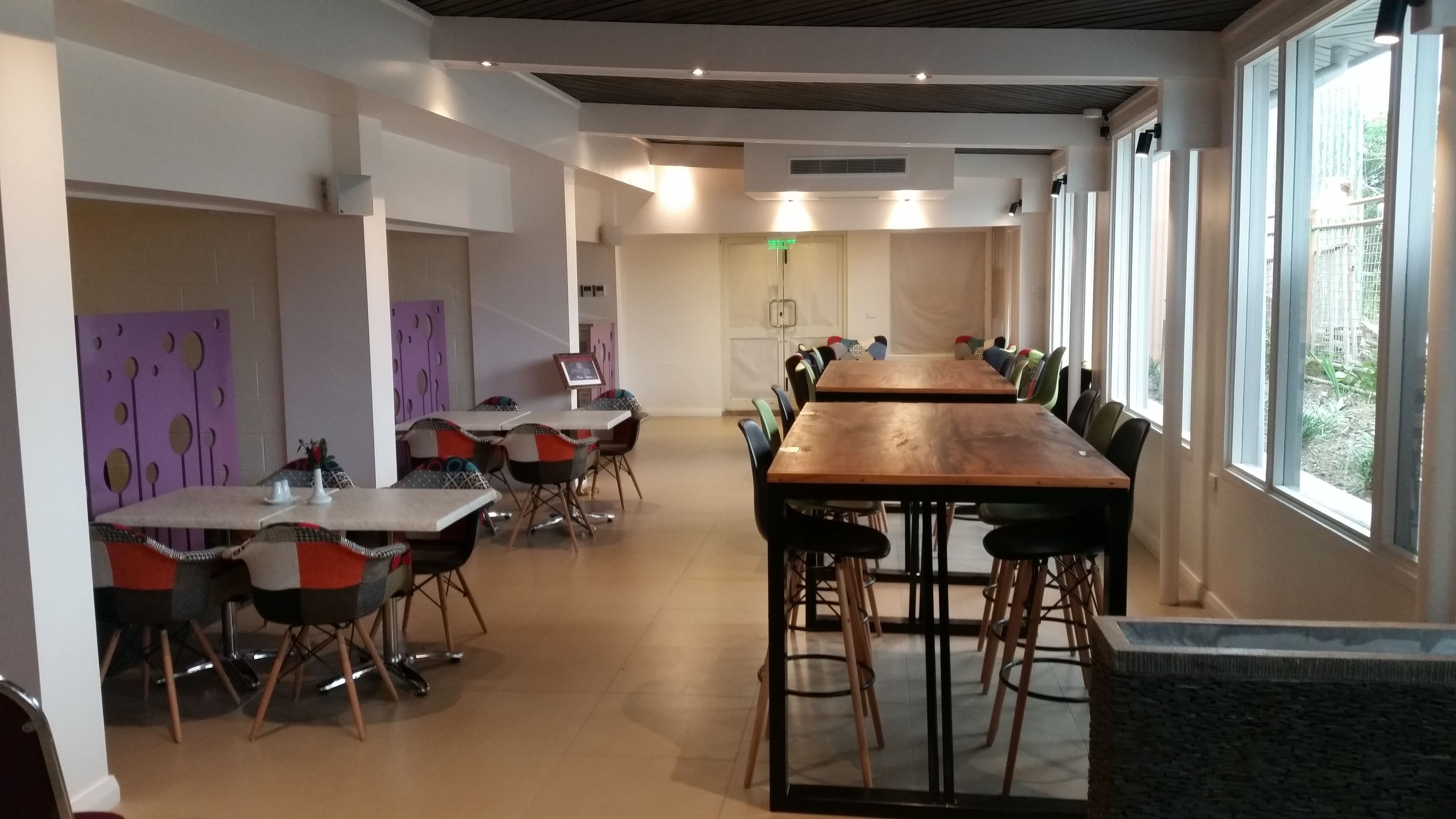 A modern dining area with long tables and chairs, large windows, and a clean, minimalist design.