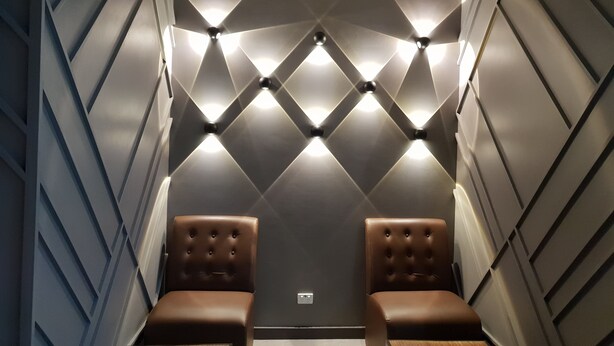 A room with a geometric wall design, two leather chairs, and a wooden table. - Peninsula International Hotel (Suva)