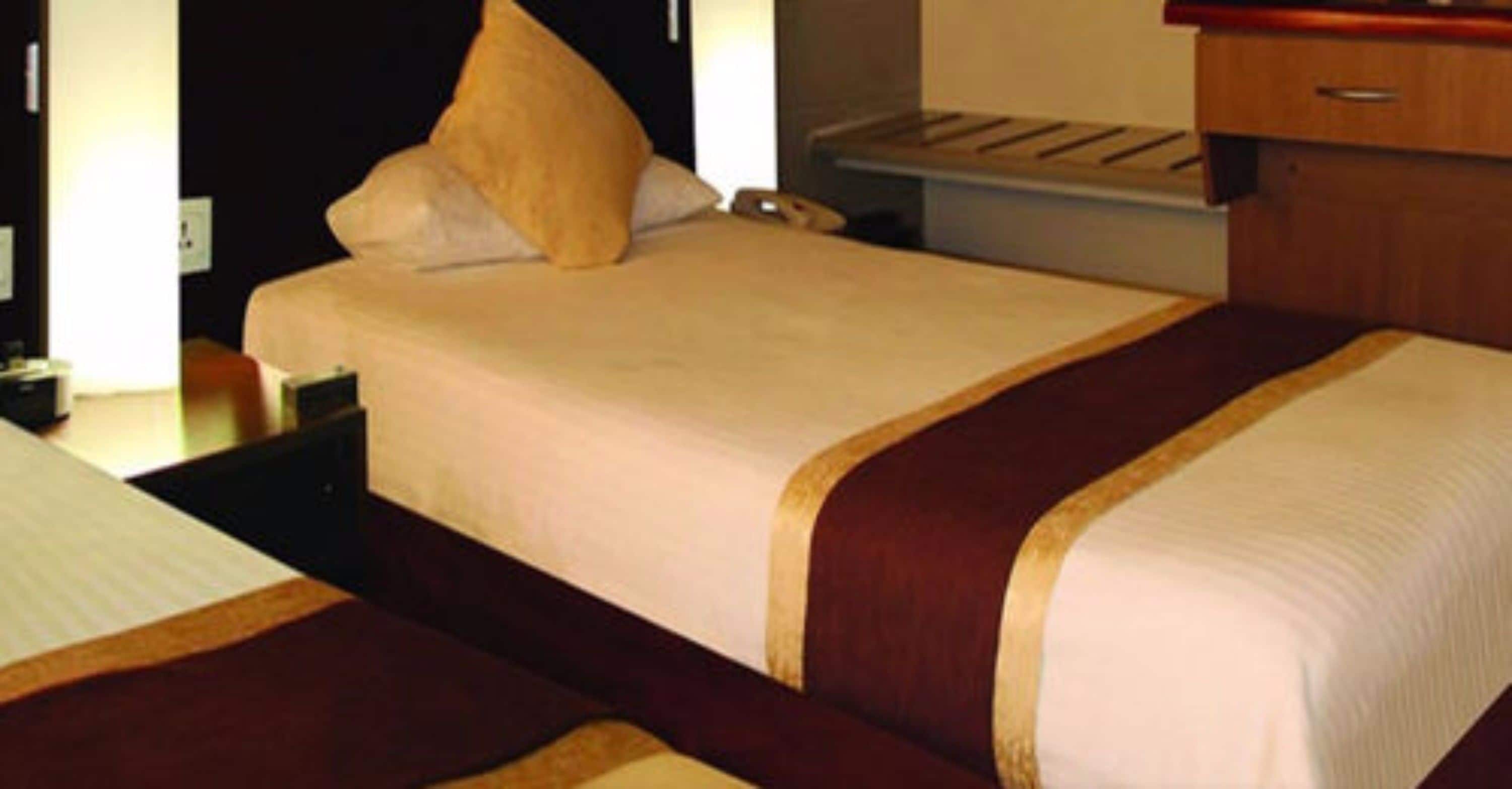 A hotel room with a bed, a nightstand, and a dresser.