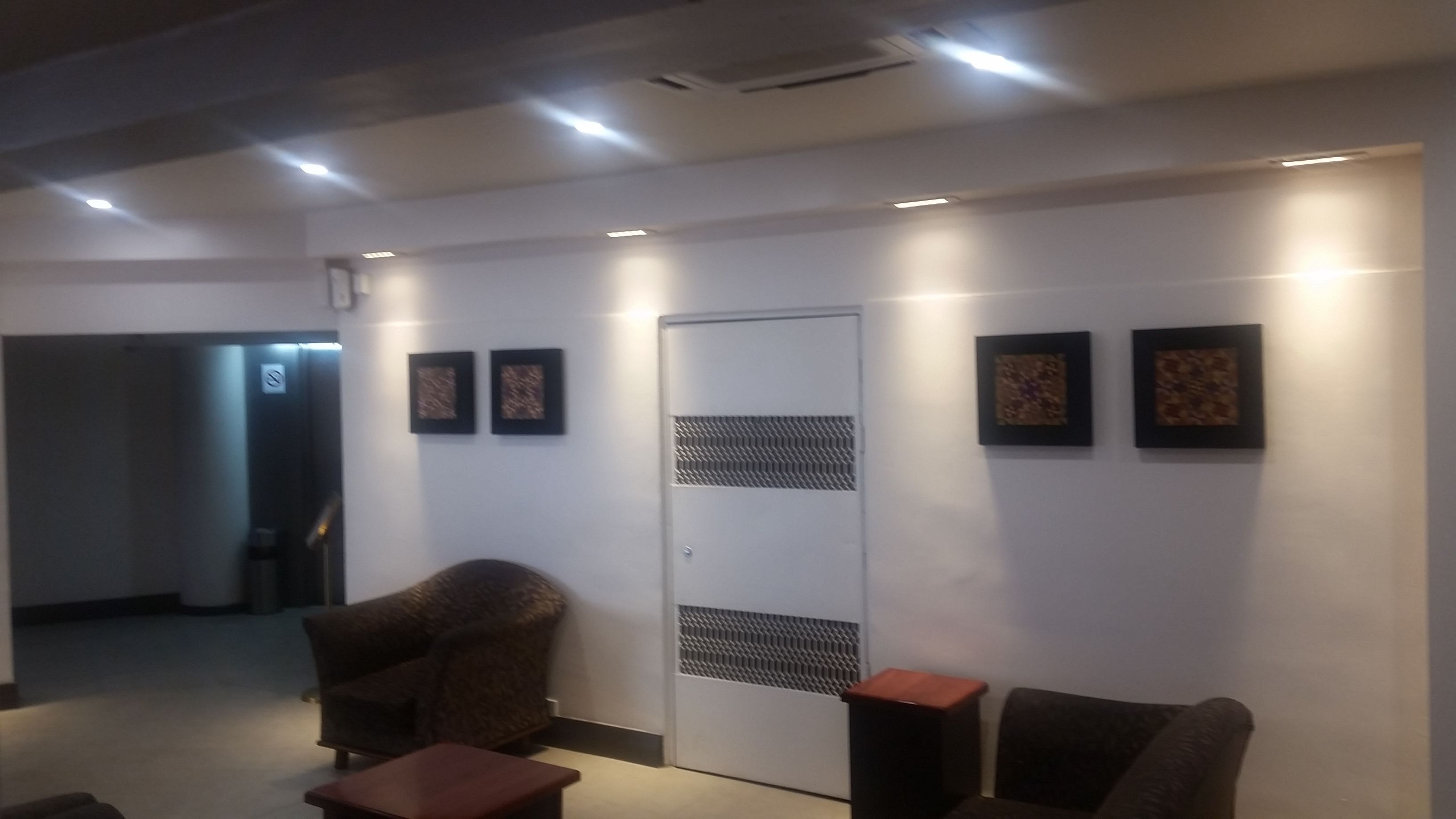 A modern waiting area with a reception desk, a seating area with two chairs, and a door with a vent.