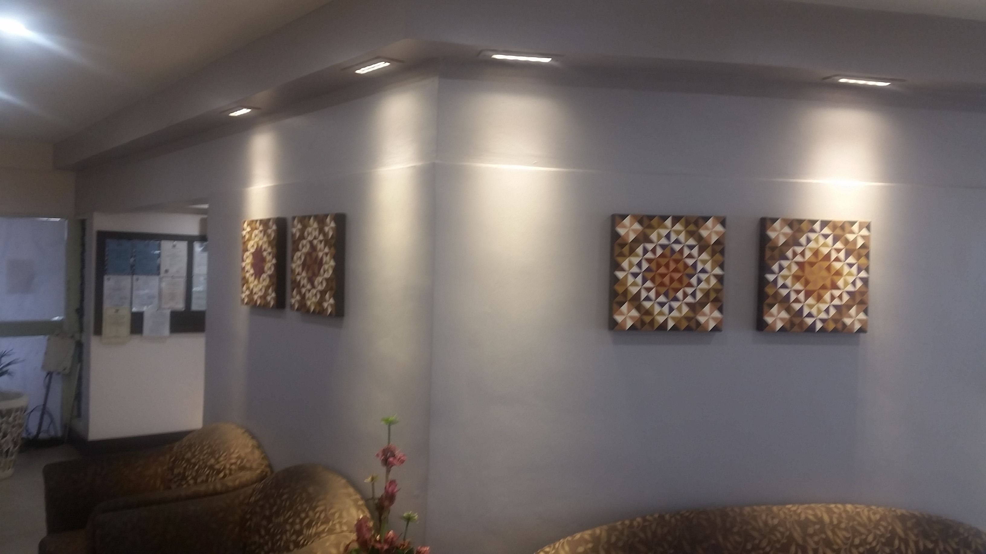 A waiting area with a sofa, a small table with a vase, and three wall-mounted artworks.
