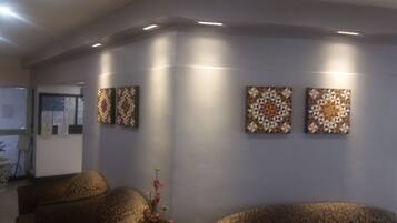 A waiting area with a sofa, a small table with a vase, and three wall-mounted artworks.