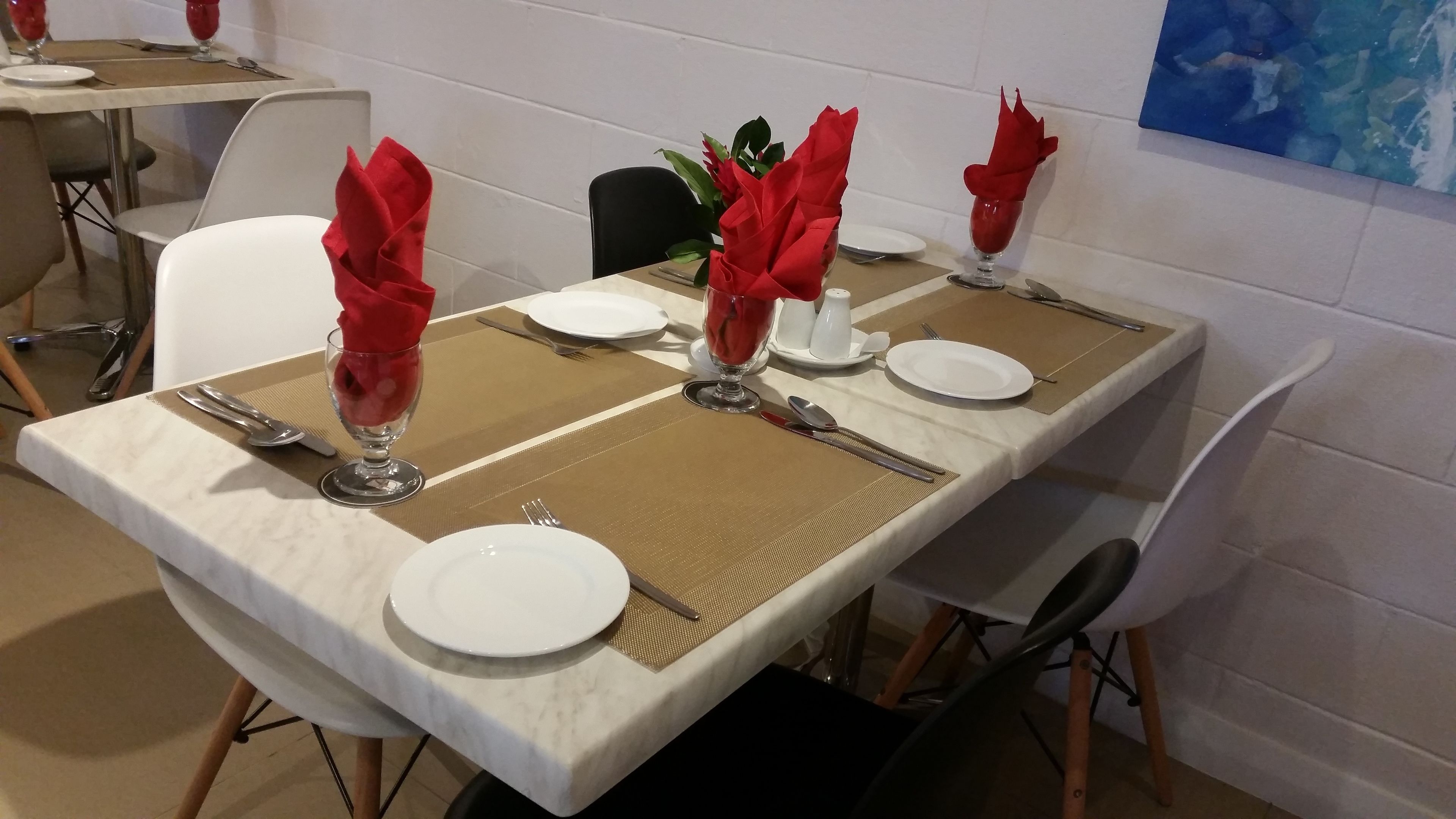 Une table à manger dressée avec de l’argenterie, des assiettes blanches et des serviettes rouges.