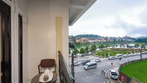 A balcony with a table and chair, overlooking a busy street with cars and a pedestrian crossing. - Canvas Sapa Legend Hotel (Sa Pa)