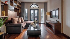 A modern living room with a sofa, a coffee table, and a TV mounted on the wall. - Canvas Sapa Legend Hotel (Sa Pa)