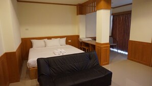 Una habitación de hotel con una cama, un sofá negro, un escritorio y una silla.