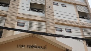 Un edificio de varios pisos con balcones, una entrada de cristal y un cartel sobre la entrada.
