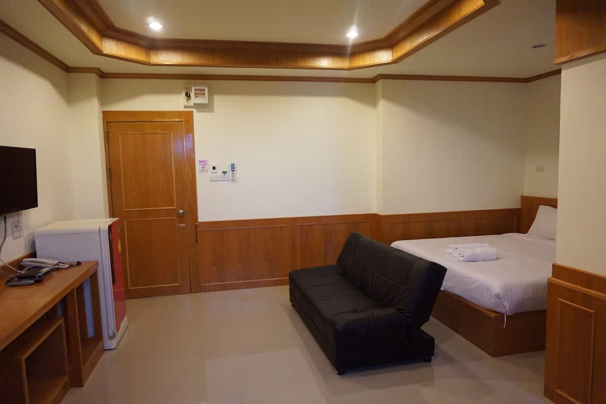 Une chambre d’hôtel avec un plafond en bois, un lit, un canapé et un bureau équipé d’un réfrigérateur.