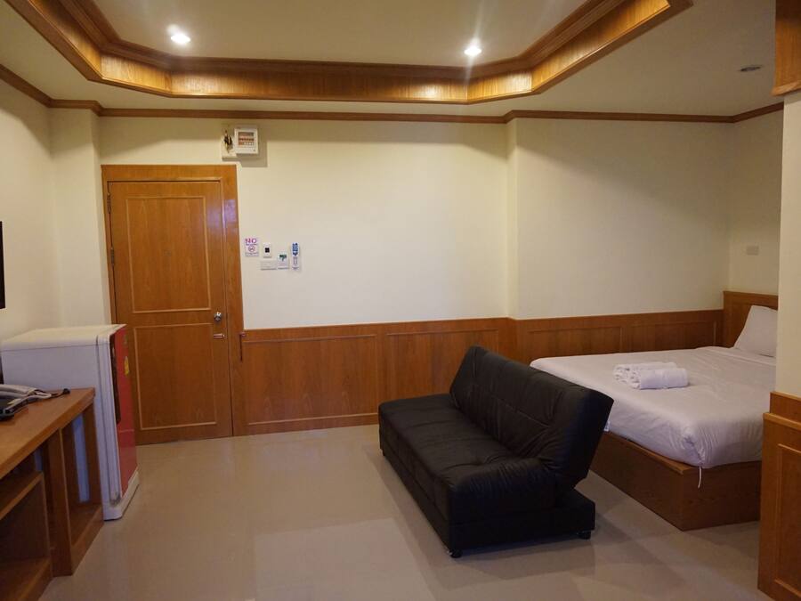 Ein Hotelzimmer mit Holzboden, einem Bett, einer Couch und einem Schreibtisch mit Kühlschrank.
