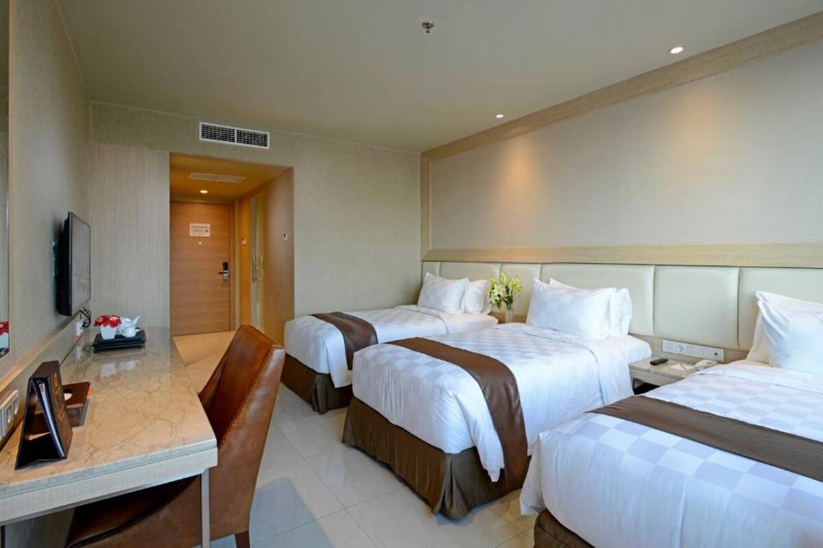 Ein Hotelzimmer mit zwei Betten, einem Schreibtisch und einem Fernseher.