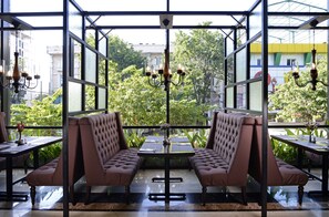 Un restaurant doté d’une verrière, de sièges rembourrés et de lustres suspendus.