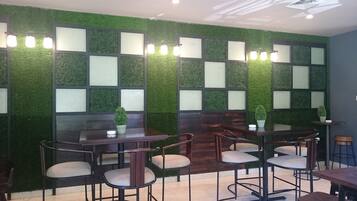 A restaurant with a green wall design, wooden tables, and chairs.