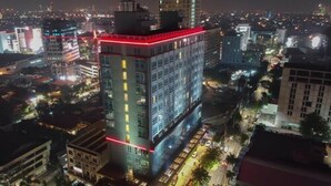 Un edifici alt amb nombrosos pisos, envoltat d'altres edificis i un paisatge urbà de nit.