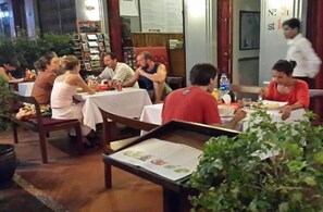 Un restaurante con varias mesas y sillas, un camarero con uniforme y un menú en cada mesa.