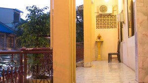 A balcony with a metal railing, a small table, and a decorative pillar. - Royal Guest House (Phnom Penh)