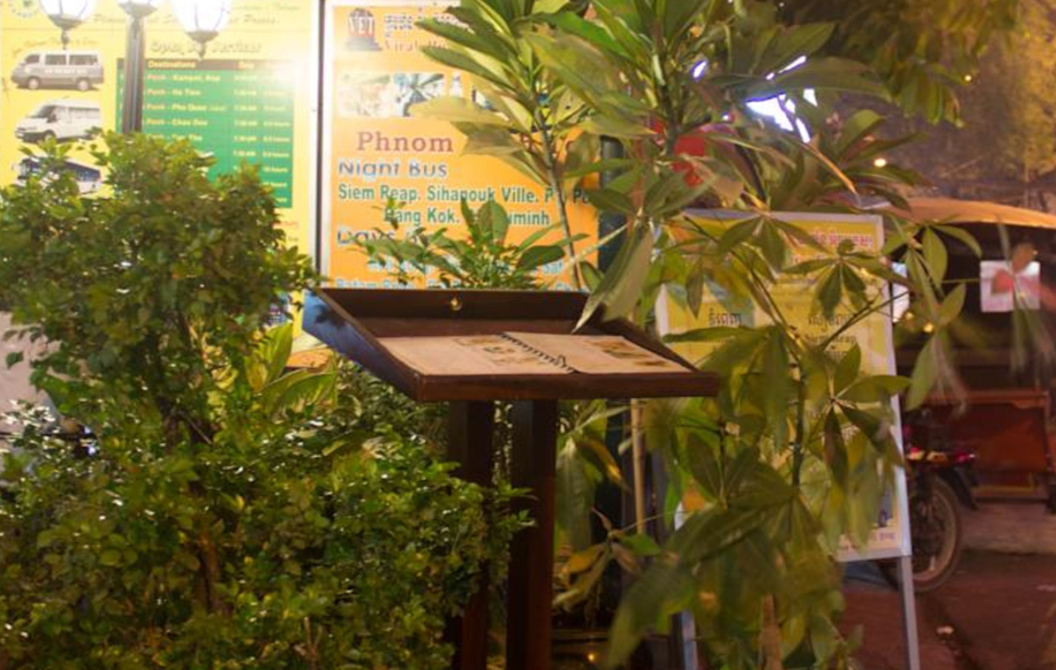 A bus stop with a signboard listing destinations.