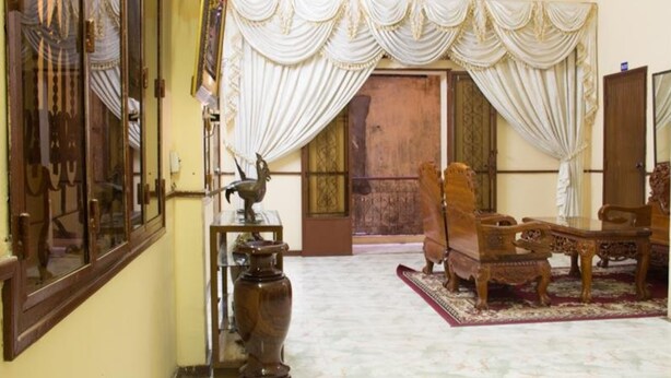 A traditional room with a wooden chair, a table, and a decorative vase. - Royal Guest House (Phnom Penh)