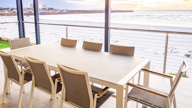 A dining area with a large table and chairs, overlooking a waterfront with a view of the city skyline. - Wallaroo Holiday Park (Wallaroo)