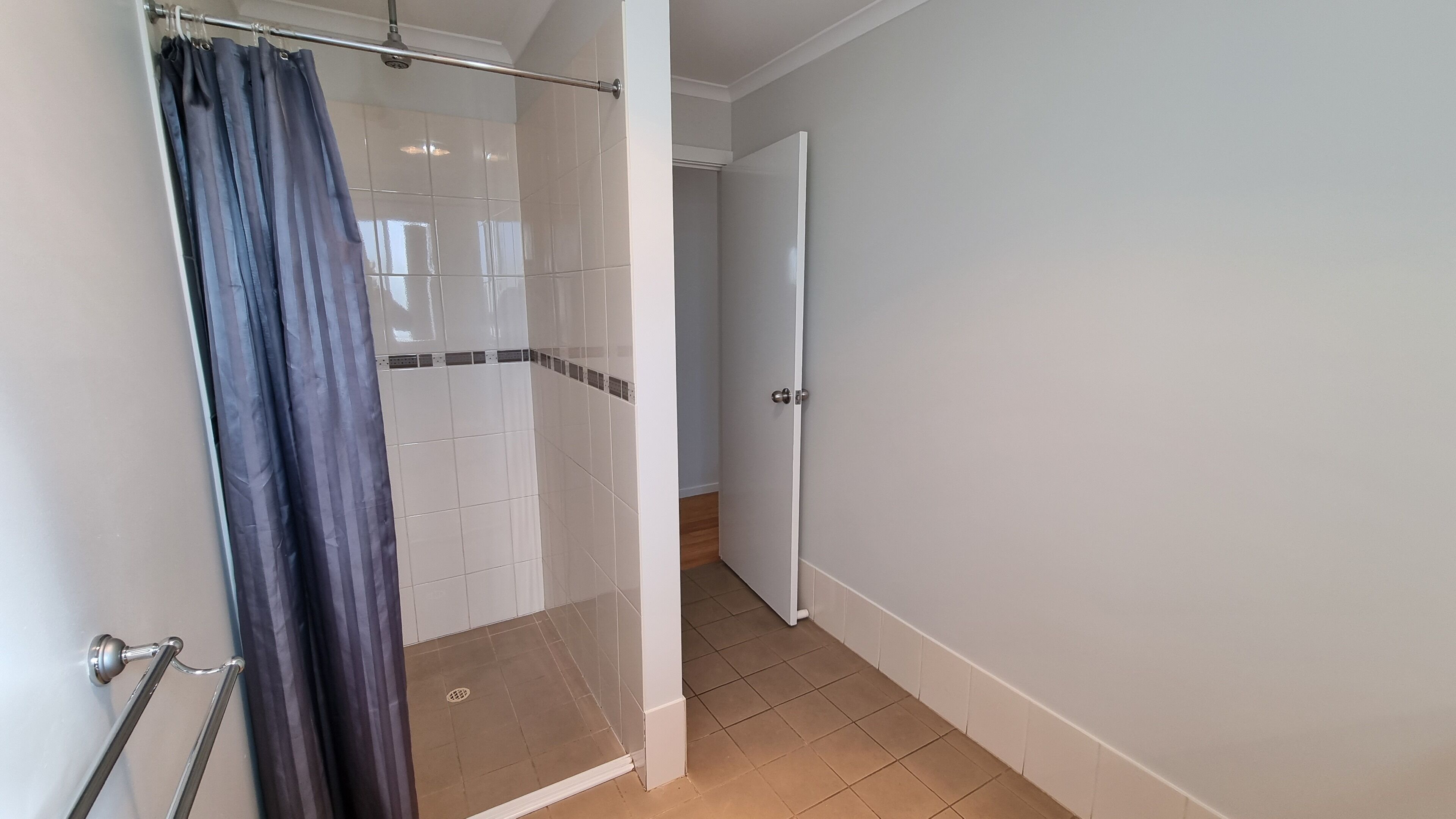 A bathroom with a shower, tiled walls, a door, and a curtain.