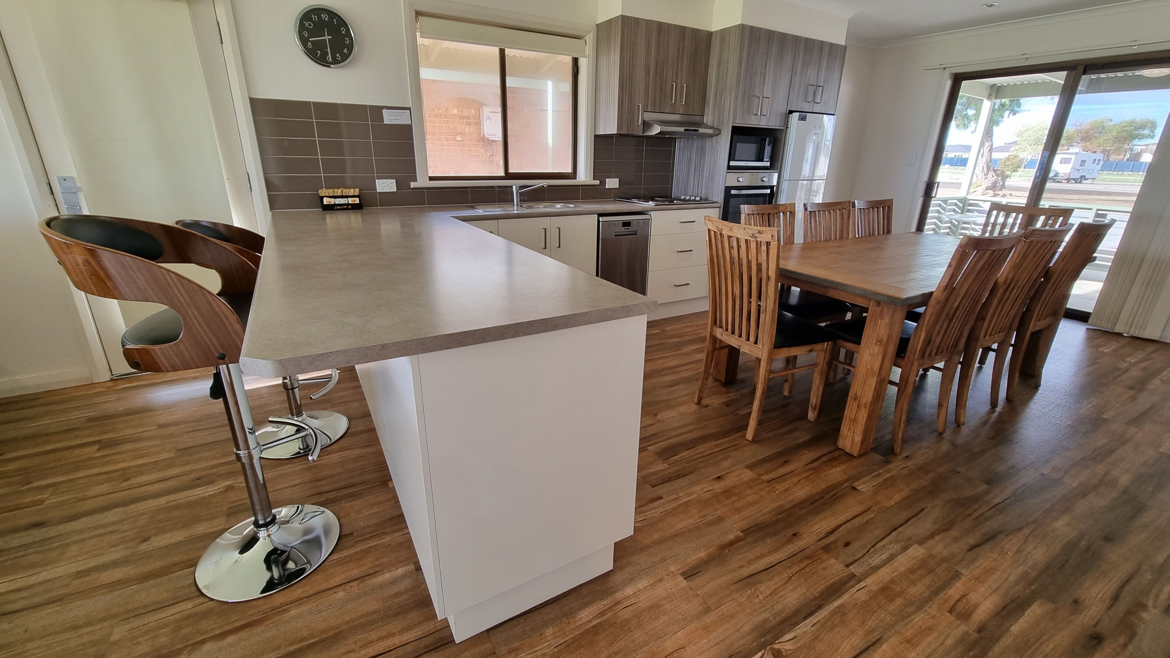 A modern kitchen with a central island, wooden dining table, and chairs.