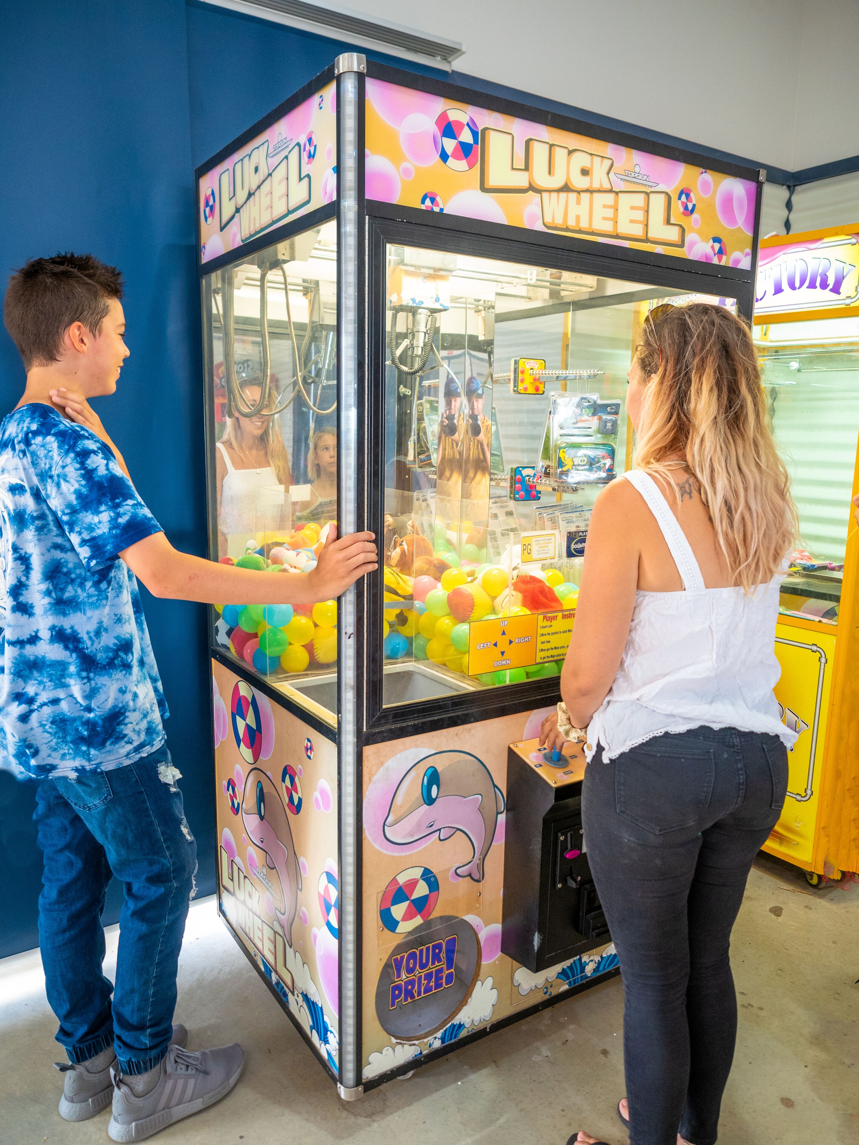 A man and a woman playing a game at a 'Luck Wheel' game booth.