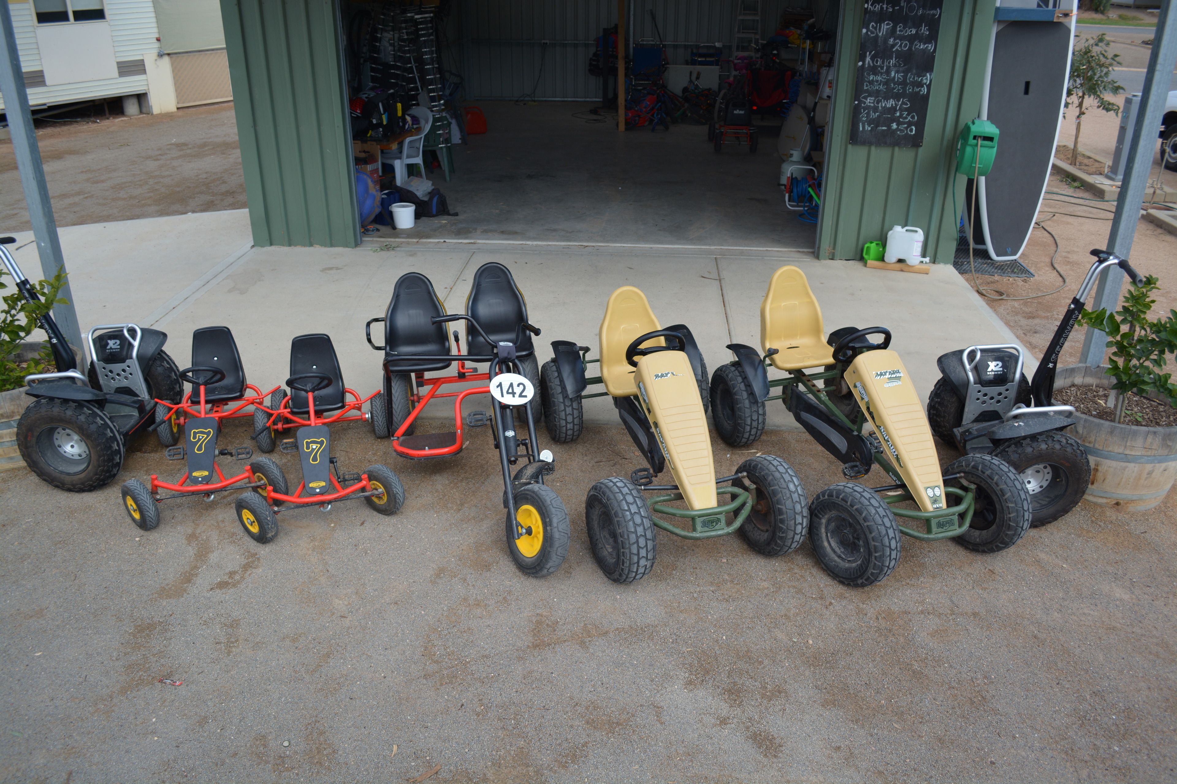 A row of quad bikes parked outside a building with a chalkboard menu.