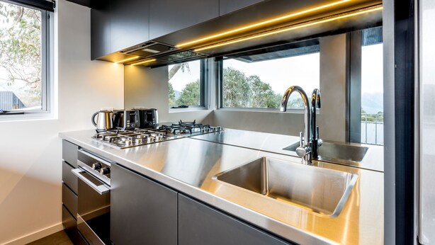 Uma cozinha moderna com eletrodomésticos de aço inoxidável, uma pia grande e uma janela com vista para o exterior.