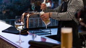 Um bartender servindo uma bebida de uma torneira em um copo.