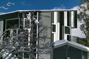 A modern building with large windows and a metal facade. - Elk at Falls (Falls Creek)