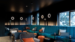 Uma área de lounge moderna com assentos, mesas e vista para a neve lá fora.
