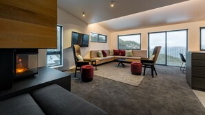 Uma sala de estar moderna com lareira, um sofá seccional e grandes janelas com vista.