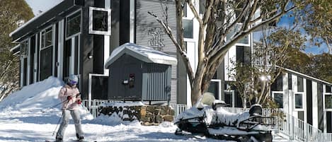Un edificio moderno con base de piedra y techo cubierto de nieve.