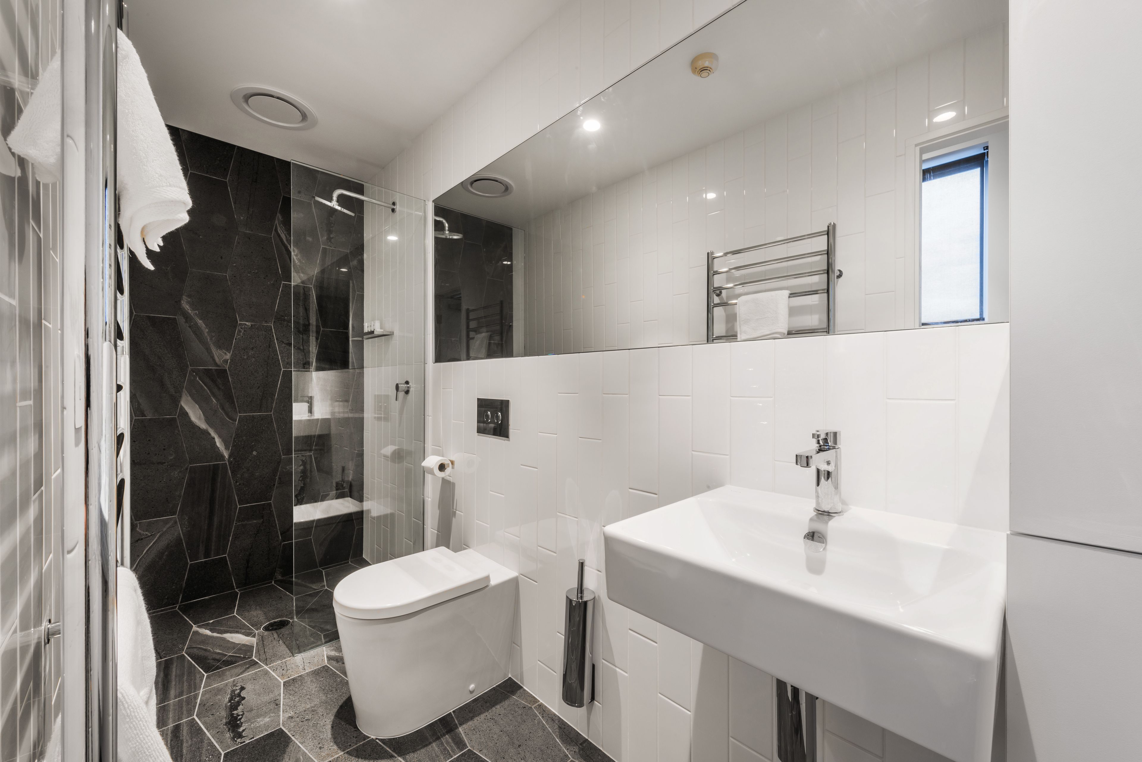 A modern bathroom with a glass-enclosed shower, a white toilet, and a large sink.